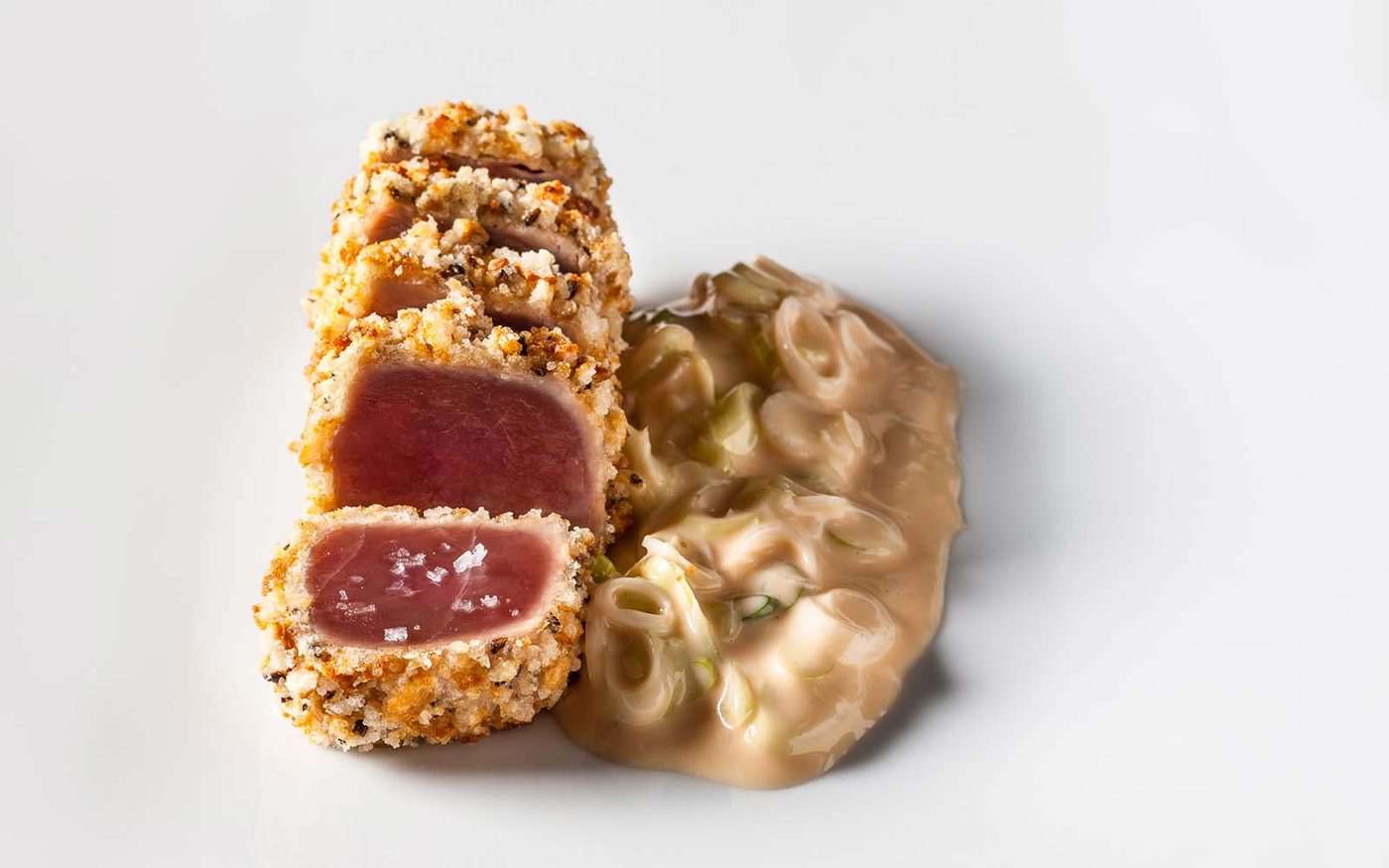 Panko-crusted seared tuna sliced to show a rare centre, finished with sea salt and served with a leek and miso sauce