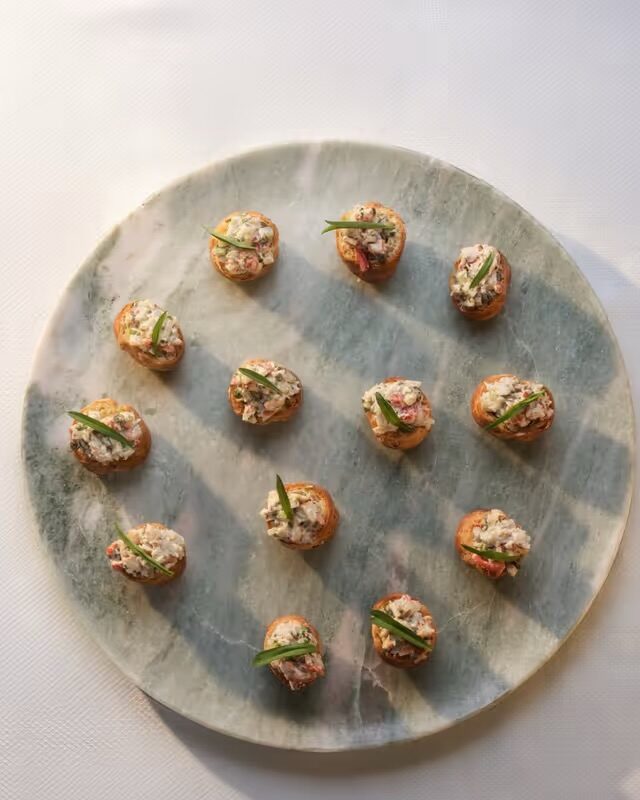 A marble platter of lobster vol-au-vents, each garnished with a single chive spear